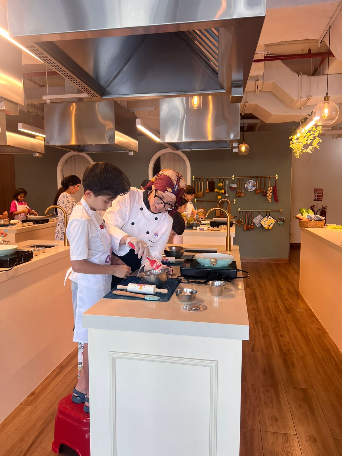 A chef guiding a young student at the main counter